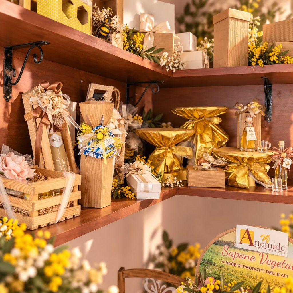 Scaffali di legno con scatole regalo, ceste e confezioni dorate, fra fiori gialli.